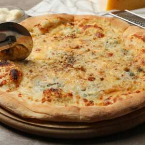 Pizza cutter and cheese pizza, close up